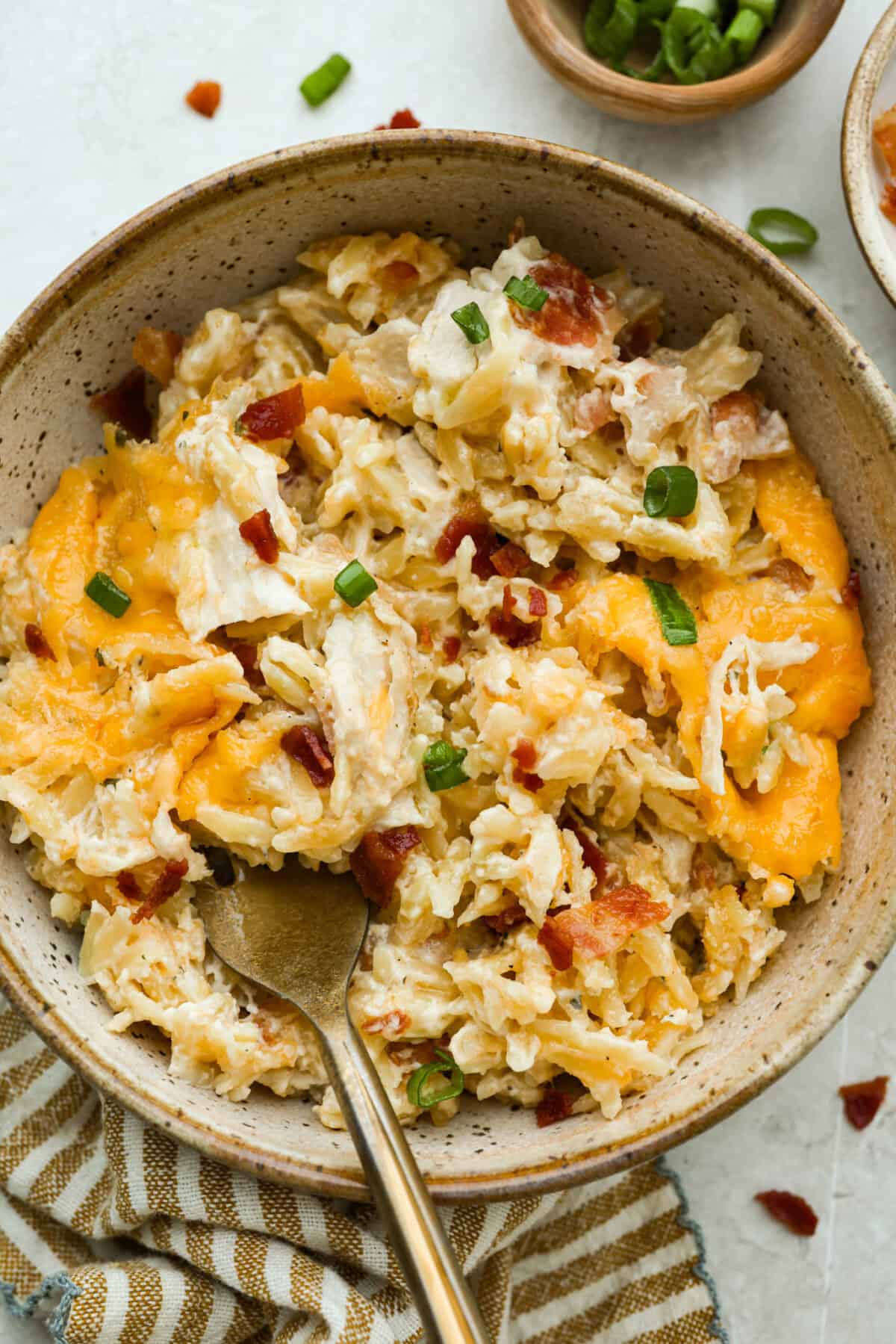 This crack orzo bake is creamy, cheesy, and packed with that irresistible ranch, bacon, and cheddar “crack” flavor everyone loves. It’s an easy casserole that’s guaranteed to be a hit. Bowl of crack chicken orzo with a gold spoon.