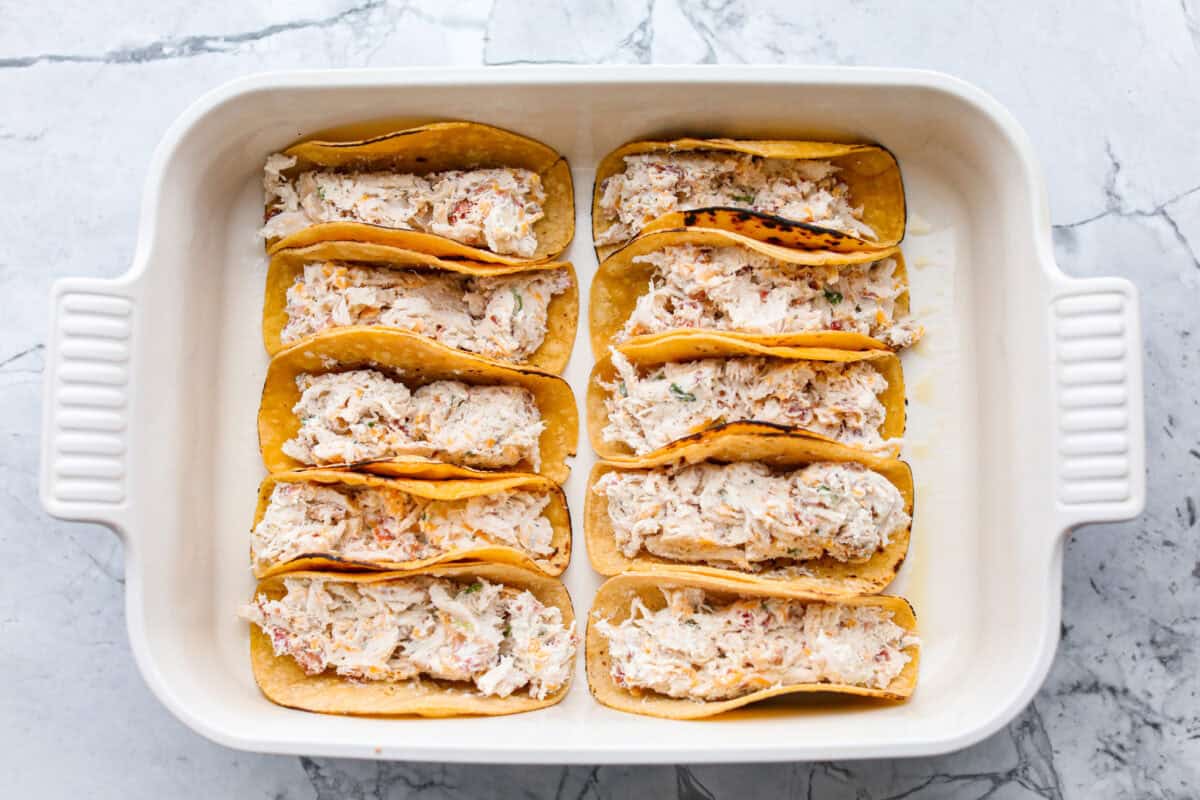 Tacos all lines up in the baking dish ready to be baked.