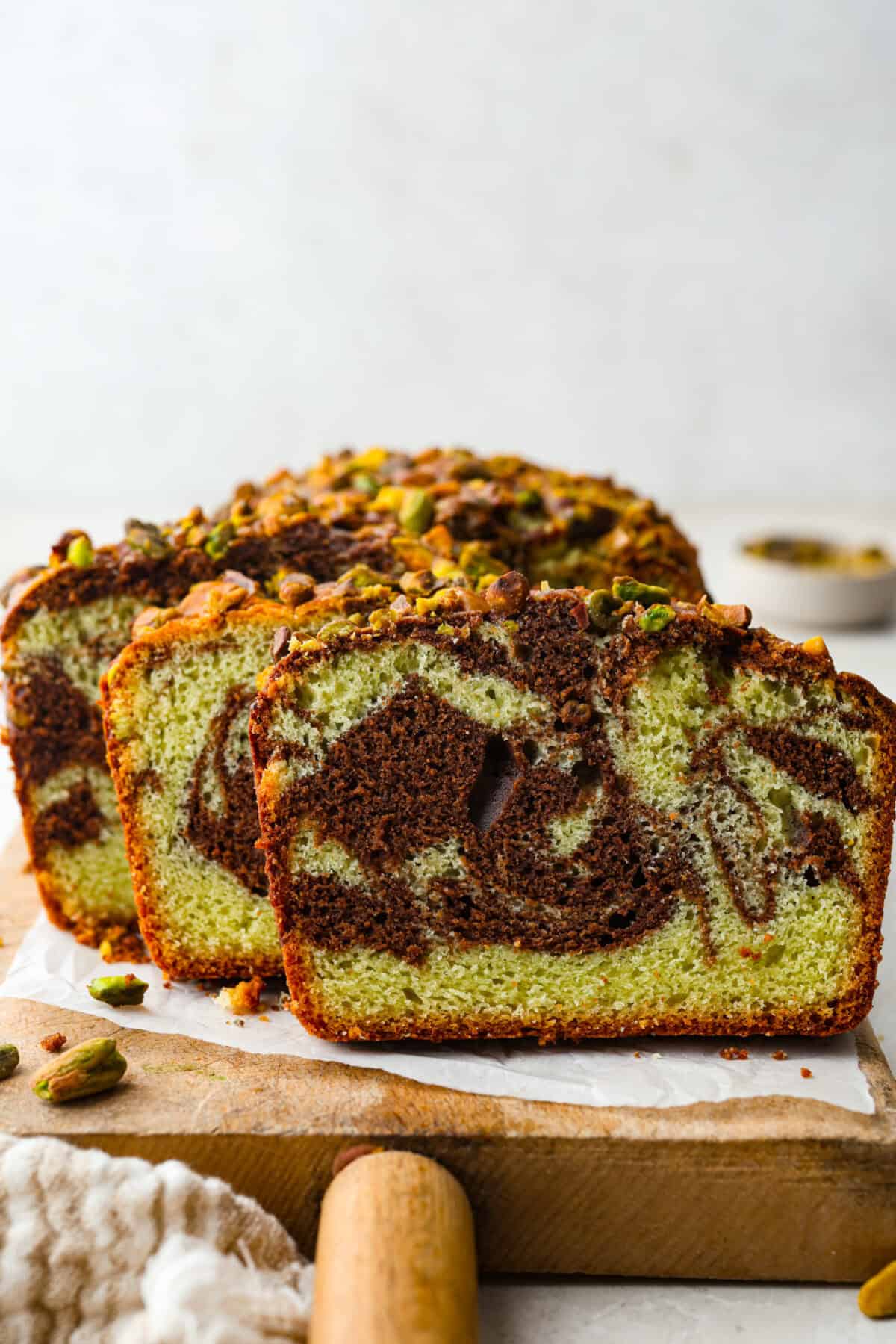 Starbucks dropped a new Chocolate Pistachio Loaf, and I was instantly obsessed. The pistachio flavor and that rich chocolate swirl had me determined to make a copycat at home so I could skip the drive-thru and bake it anytime. Side view of sliced chocolate pistachio loaf on a cutting board.