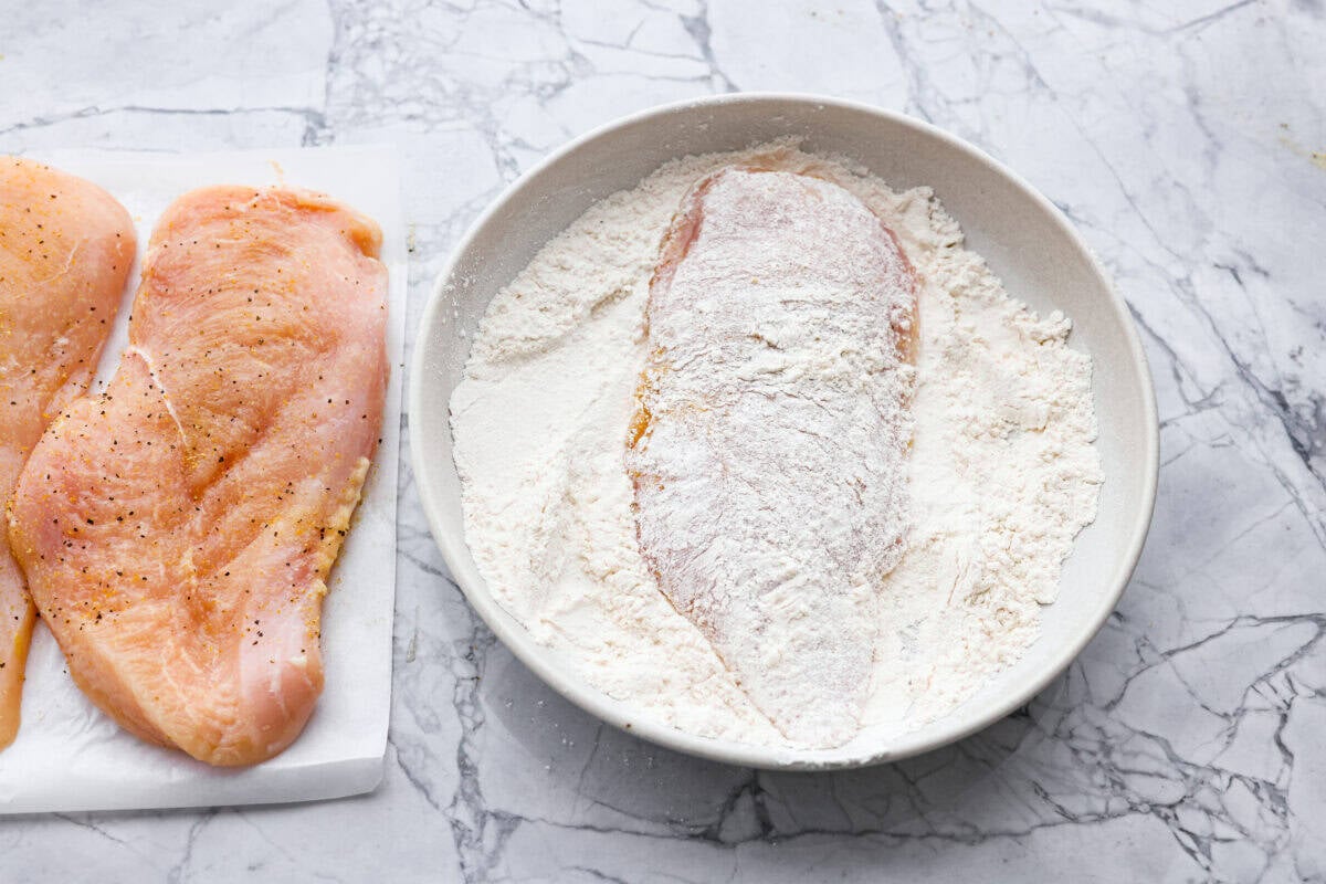Chicken breast coated in flour in a dish. 