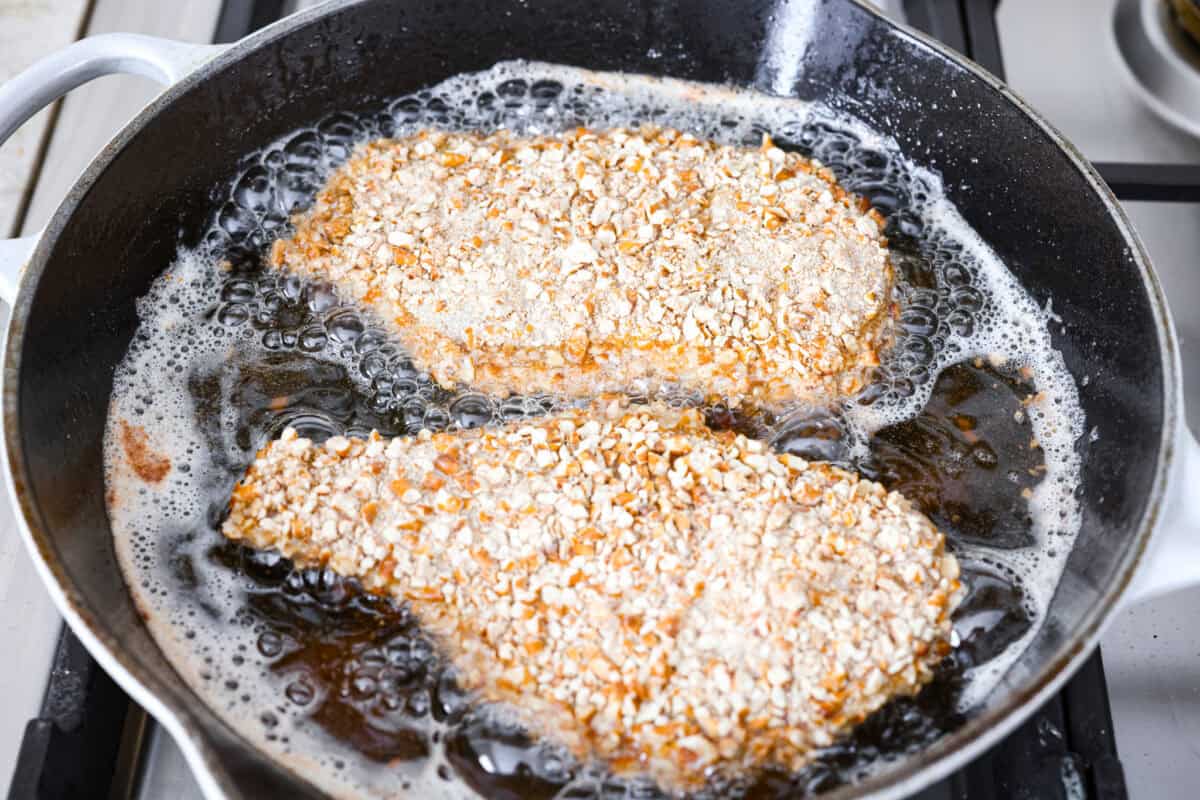This pretzel crusted chicken takes crispy chicken to the next level. The crunchy pretzel coating adds incredible flavor and texture, making every bite extra delicious. Pretzel crusted chicken coated and frying in a skillet.