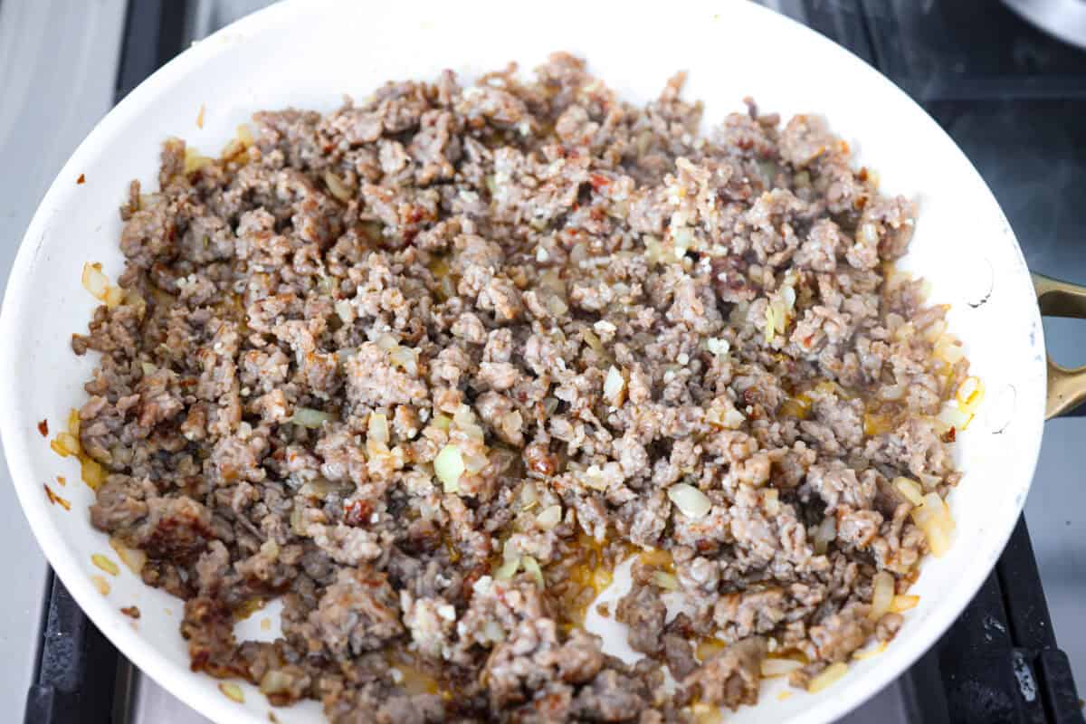 Sausage and onions cooked in a skillet.