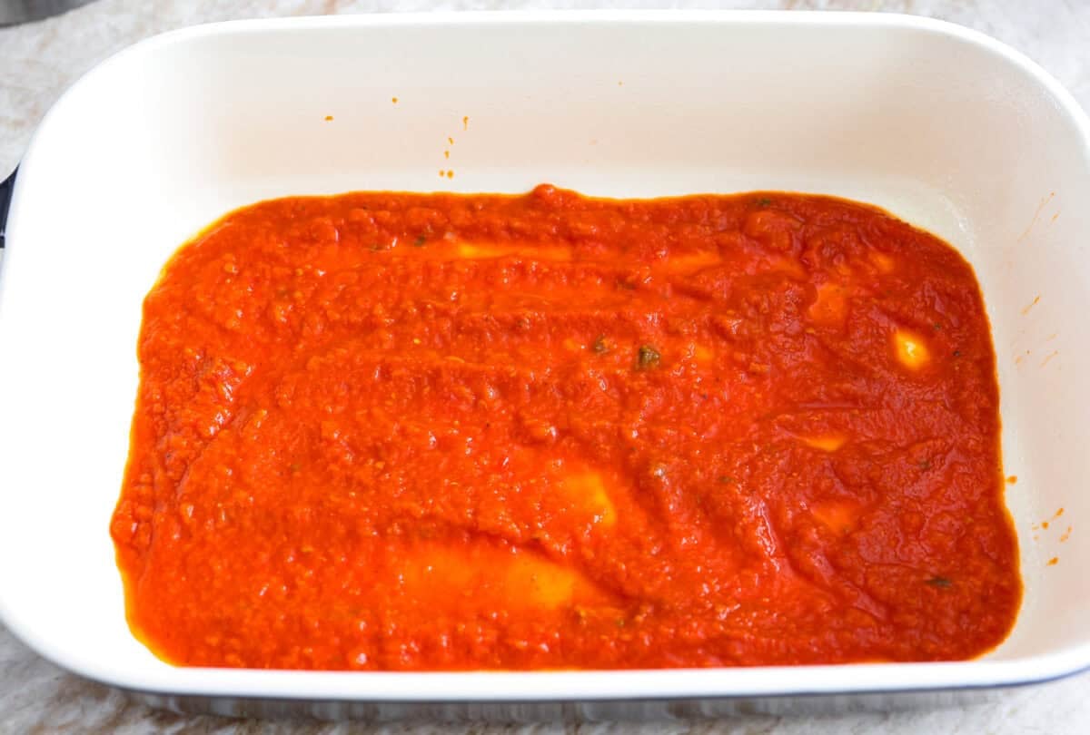 Marinara sauce added to the bottom of a baking dish. 