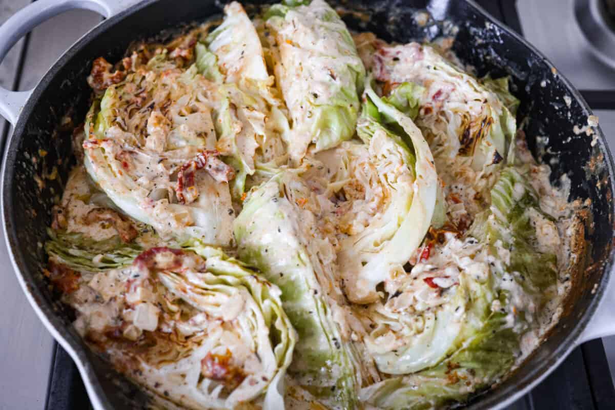 Groceries are expensive right now, so I’ve been leaning hard on the cheap staples. This melting cabbage with a garlicky cream sauce, sun-dried tomatoes, and Parmesan is easy, budget friendly, and tastes amazing. Cabbage wedges ready to be covered and placed in the oven to bake.
