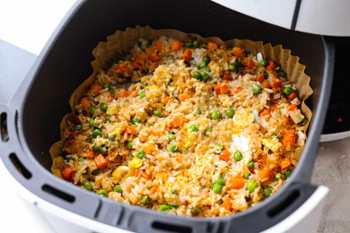 Cooked eggs stirred into the rice mixture in the air fryer basket. 