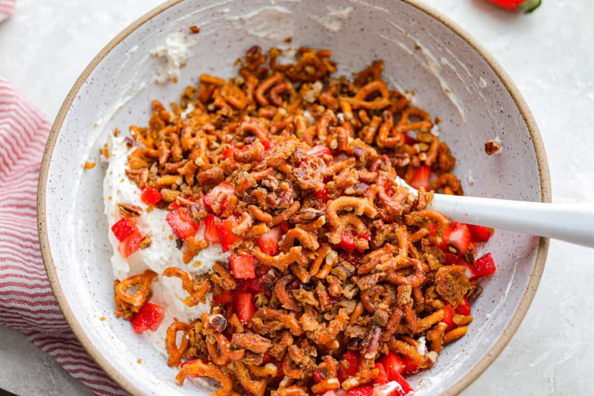 All of the strawberry pieces, pretzel mixture, and cream cheese mixture added to a bowl to be stirred together. 