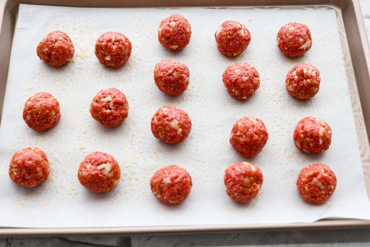 These sweet and sour meatballs are one of those dinners I pull out when I need something easy, but I know everyone likes! They’re saucy, a little sweet, a little tangy, and come together fast. Meatballs mixed and formed into balls on a parchment lined cookie sheet.