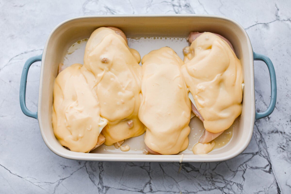 Okay, this Swiss Chicken Casserole is my go-to when I don’t feel like cooking. You basically throw it together, pop it in the oven, and somehow end up with super tender chicken, melty Swiss cheese, and the creamiest sauce. Soup mixture spread over the cheese on top of the chicken breasts.