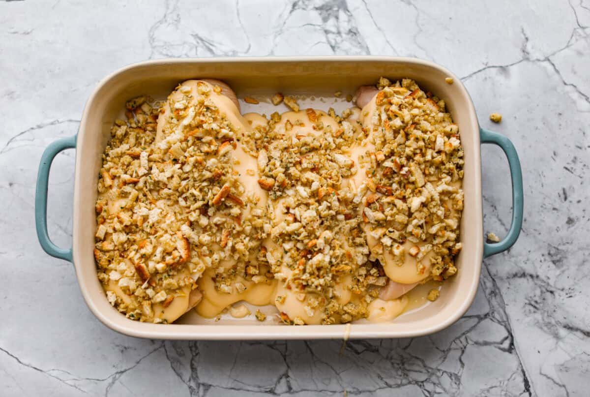 Okay, this Swiss Chicken Casserole is my go-to when I don’t feel like cooking. You basically throw it together, pop it in the oven, and somehow end up with super tender chicken, melty Swiss cheese, and the creamiest sauce. Stuffing mix added to the top of the chicken, ready to go in to oven.